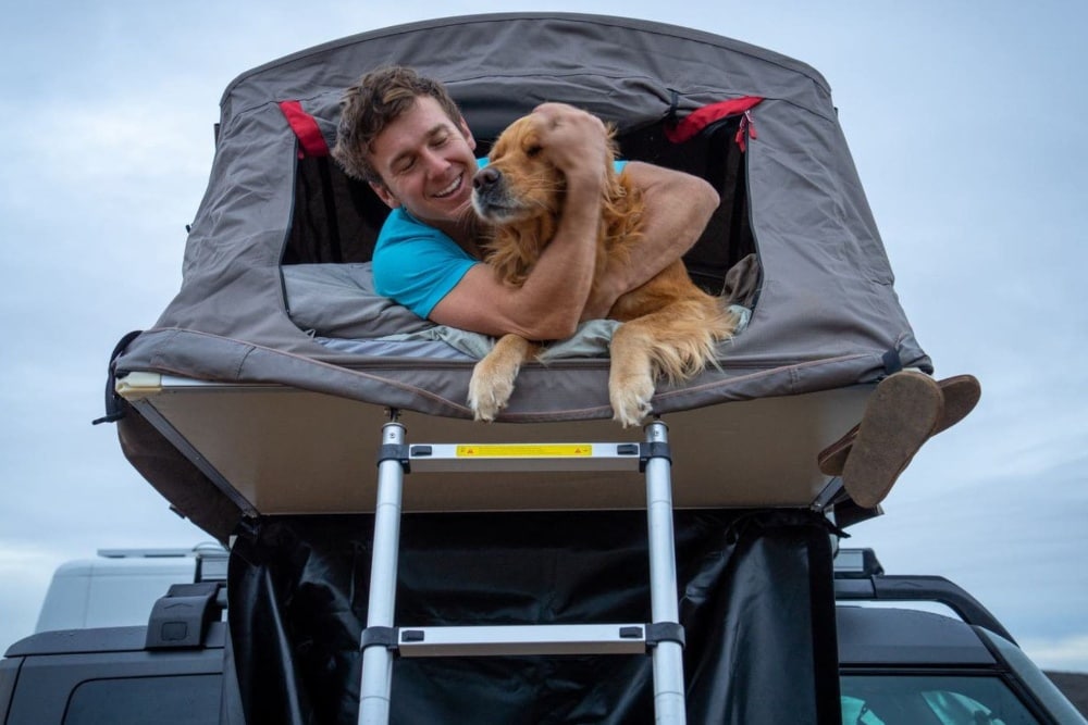 Homem com o seu cão no tejadilho de um Ford