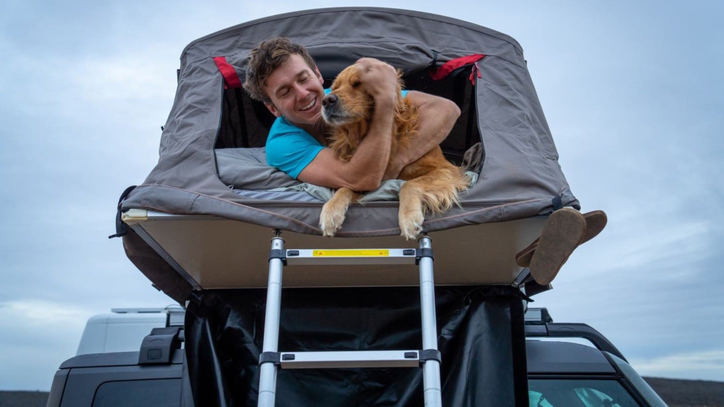 Homem com o seu cão no tejadilho de um Ford