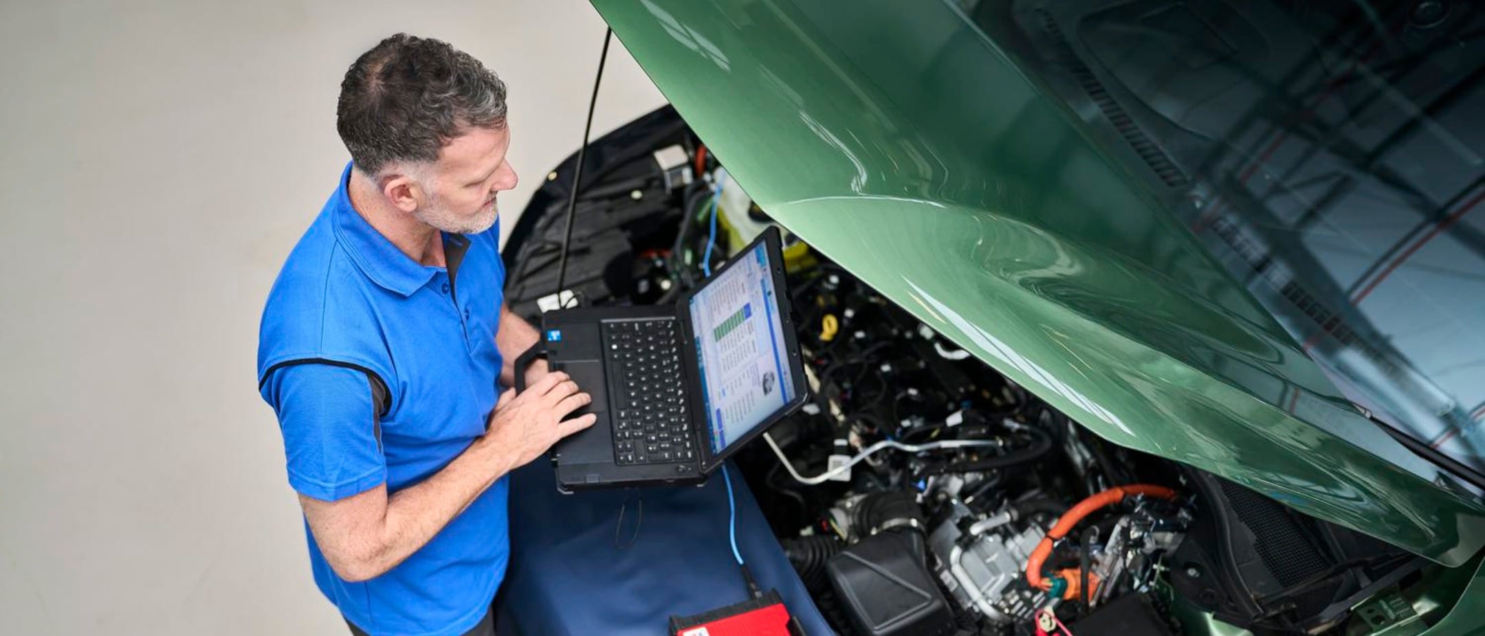 Ford Puma cinzento claro ou azul celeste com teto preto, circulando em movimento numa rua urbana ensolarada com o fundo desfocado.
