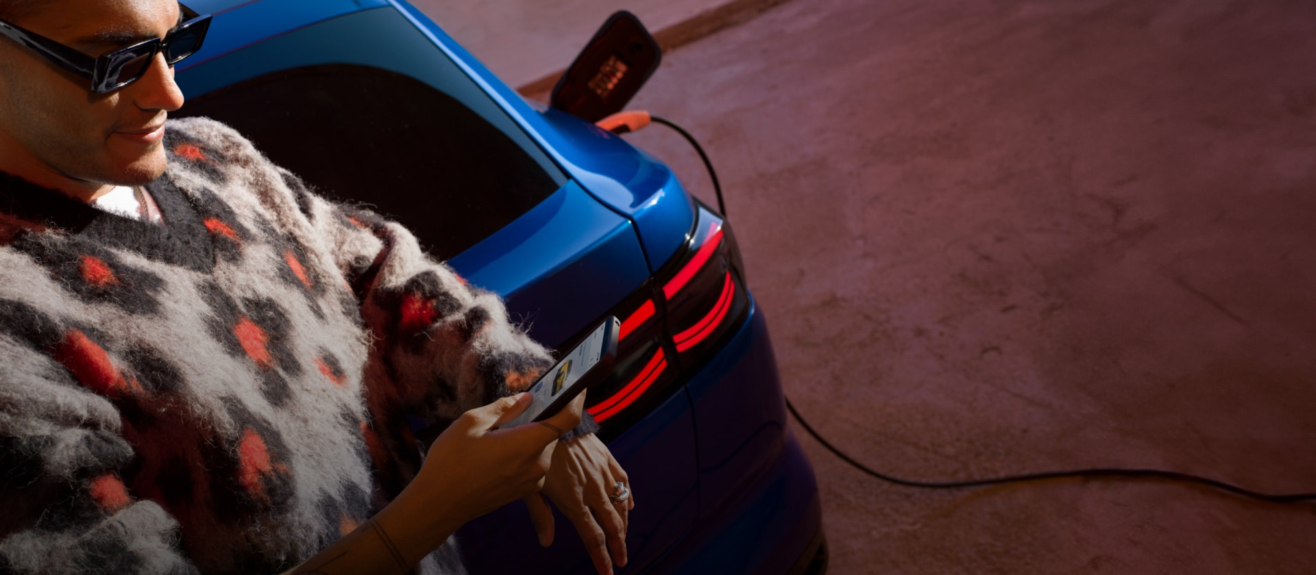 Uma pessoa carregando um Ford Capri EV azul em uma estação de carregamento pública.