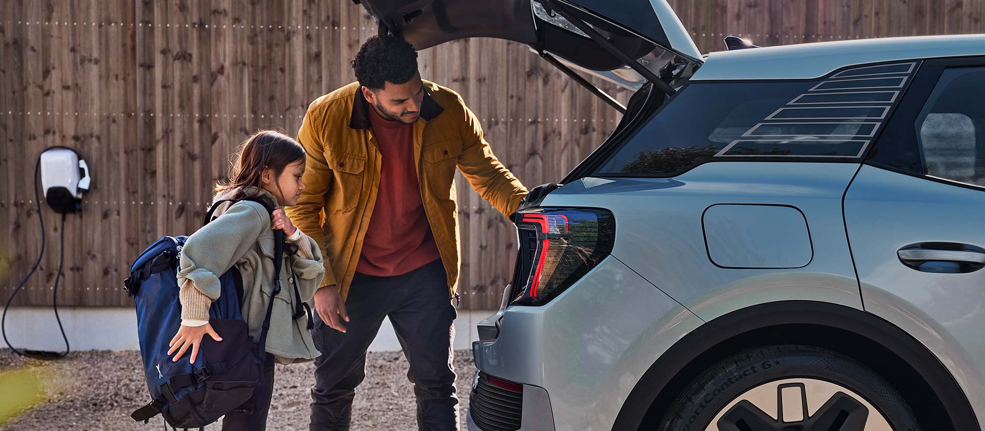 Uma família carregando o porta-malas de um Ford Explorer elétrico azul.