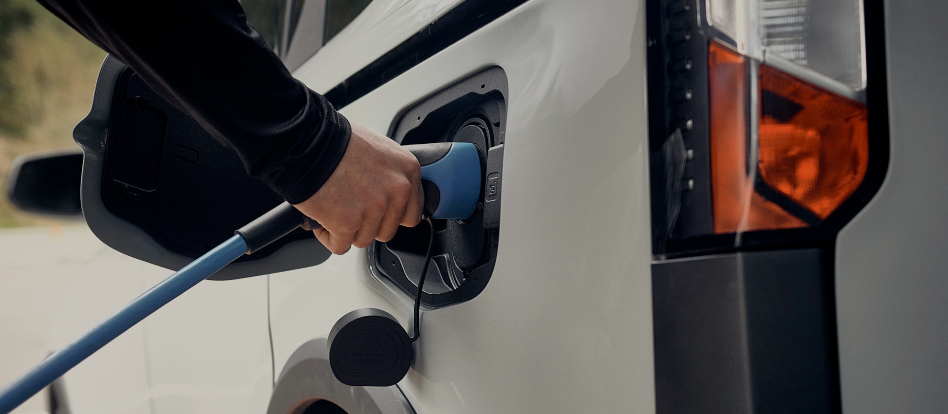 Close-up de um veículo elétrico Ford branco sendo conectado a um carregador de EV.
