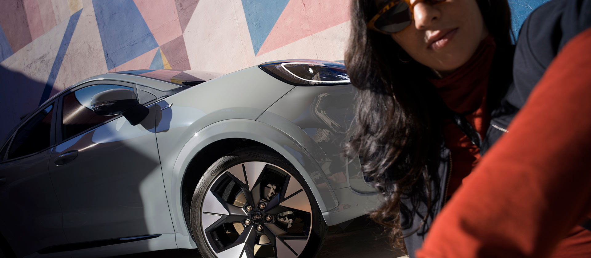 Uma pessoa sentada ao lado de um Ford Puma híbrido leve prateado.