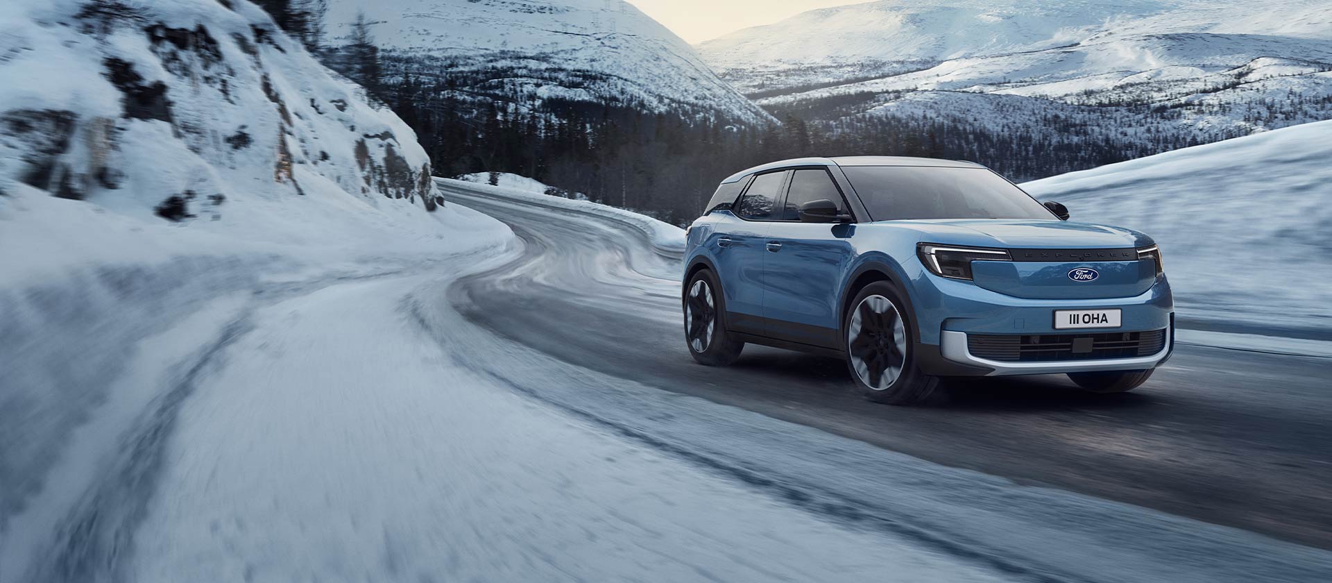 Ford Explorer elétrico azul em uma estrada de montanha nevada, destacando sua capacidade e alcance em condições de inverno.