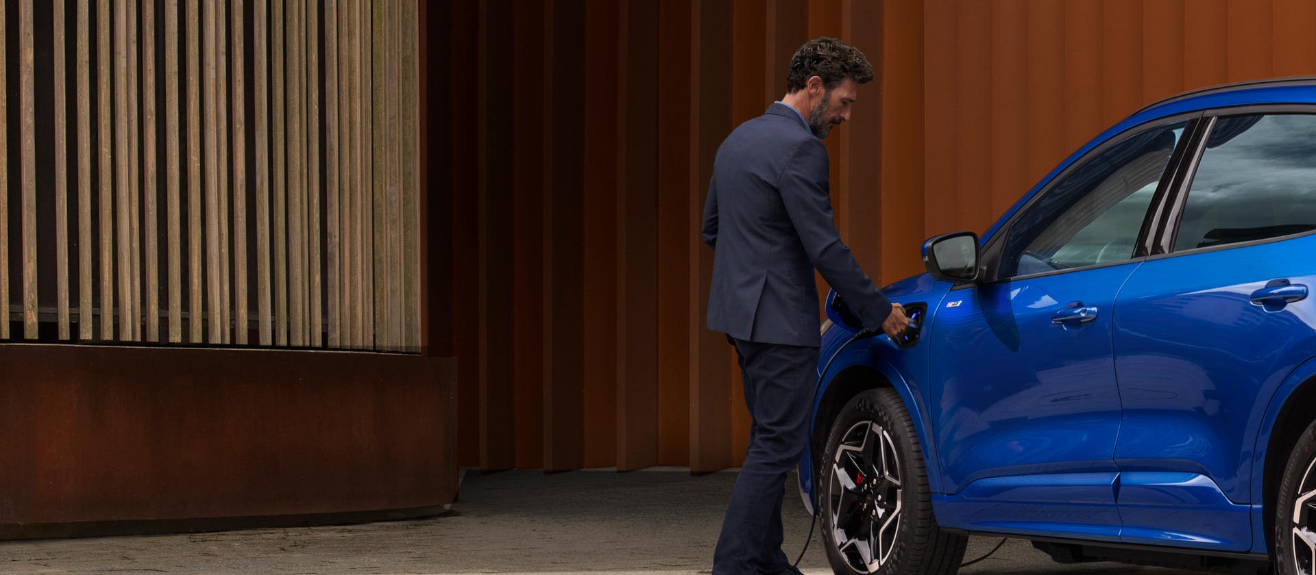 Uma pessoa conectando um carro híbrido plug-in da Ford a um cabo de carregamento doméstico EV.