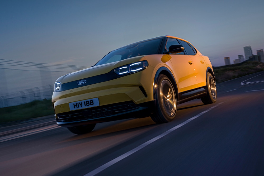 Um carro elétrico amarelo Ford Capri dirigindo ao longo de uma estrada aberta.