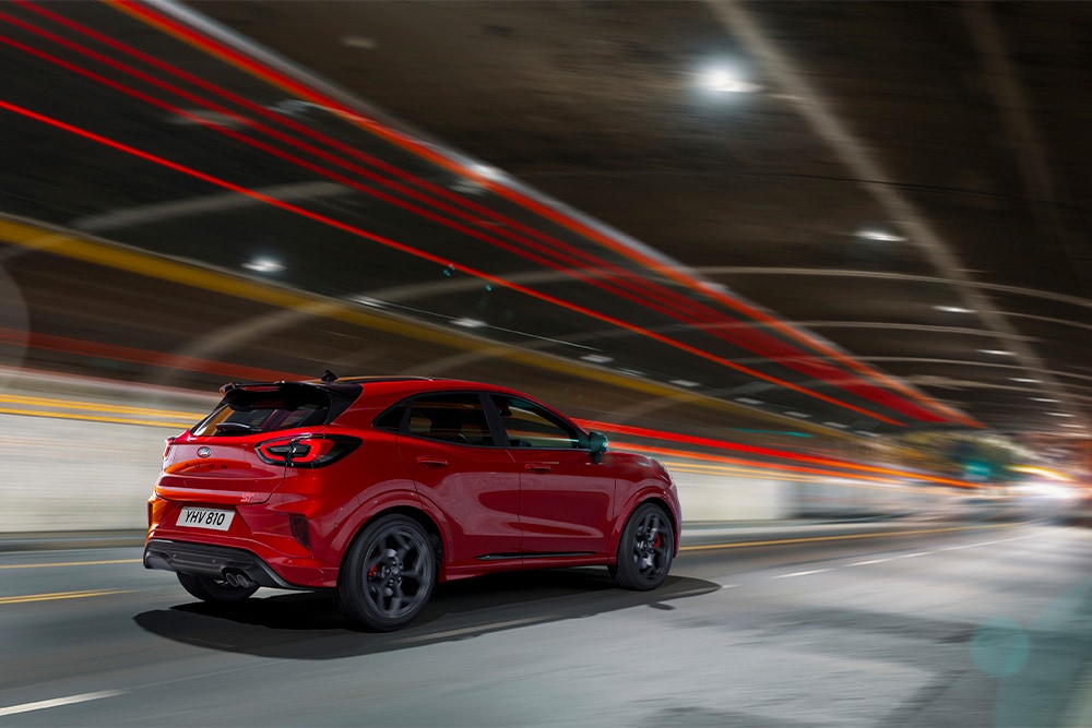 Um Ford Focus híbrido leve vermelho dirigindo através de um túnel.