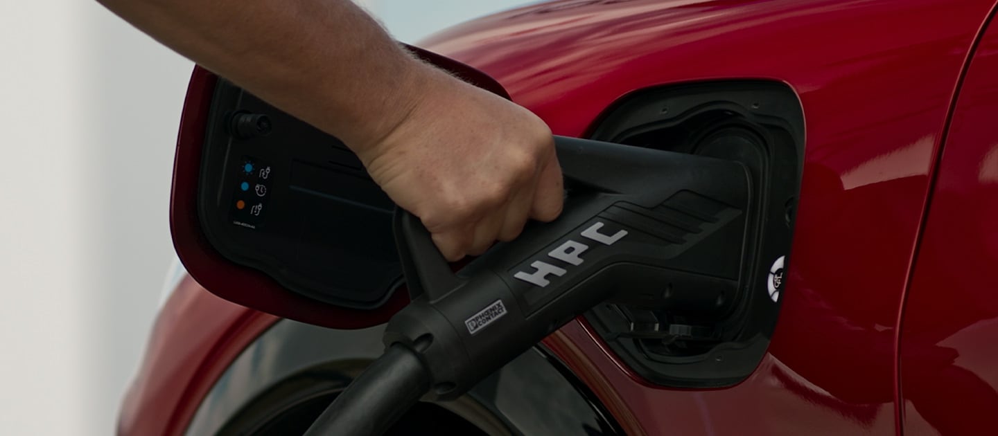 Close-up de um Ford EV vermelho a ser ligado a um HPC (High Power Charger) público, para carregamento rápido de veículos elétricos públicos.