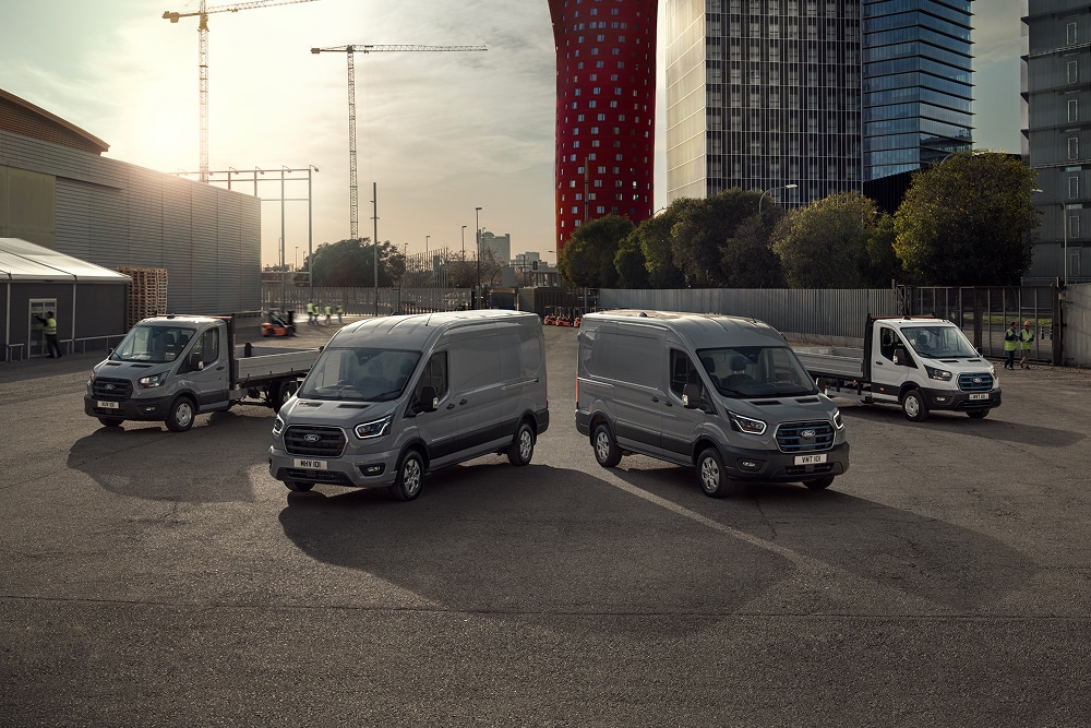 Gama de furgões elétricos e híbridos plug-in da Ford estacionados no exterior de um parque de estacionamento.