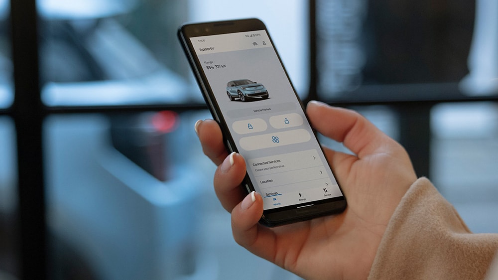 Grande plano de uma mão a segurar um smartphone e a interagir com a FordPass app.