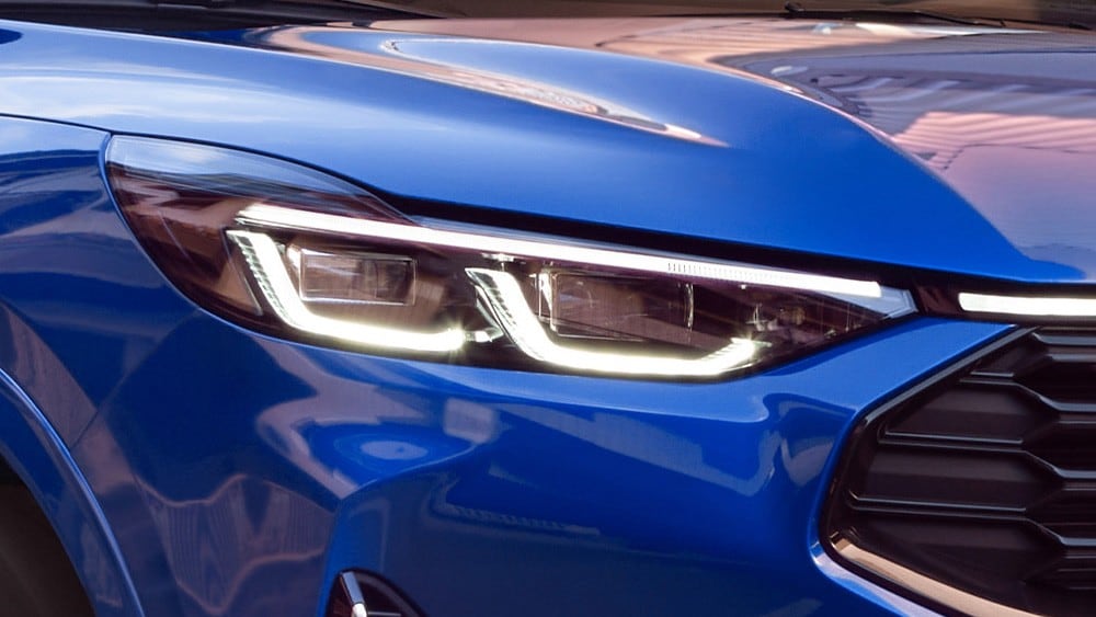 Grande plano do farol dianteiro de um Ford Mustang Mach-E azul.