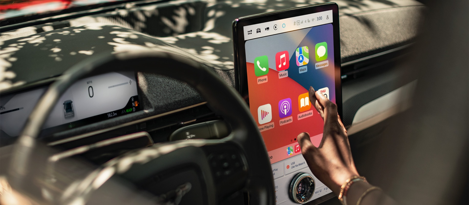 Grande plano de condutor do Ford Mustang Mach-E a interagir com o grande ecrã tátil SYNC 4 de 15,5" a mostrar Apple CarPlay.