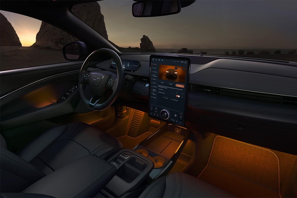 Interior do Ford Mustang Mach-E à noite, a mostrar o ecrã tátil SYNC 4 de 15,5" e a iluminação LED ambiente laranja
