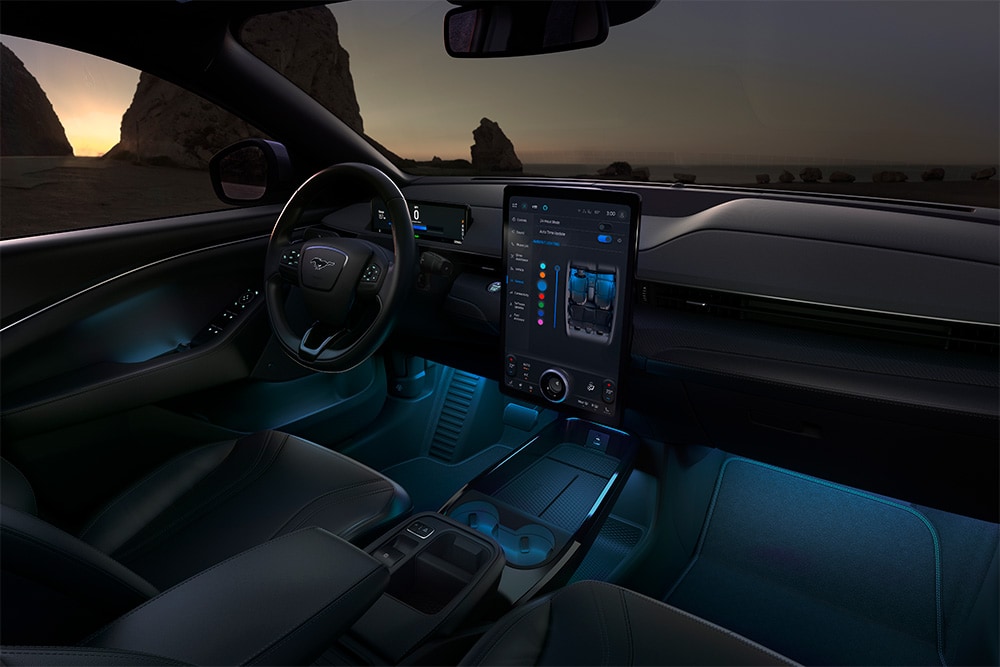 Interior do Ford Mustang Mach-E à noite, a mostrar o ecrã tátil SYNC 4 de 15,5" e a iluminação LED ambiente azul.