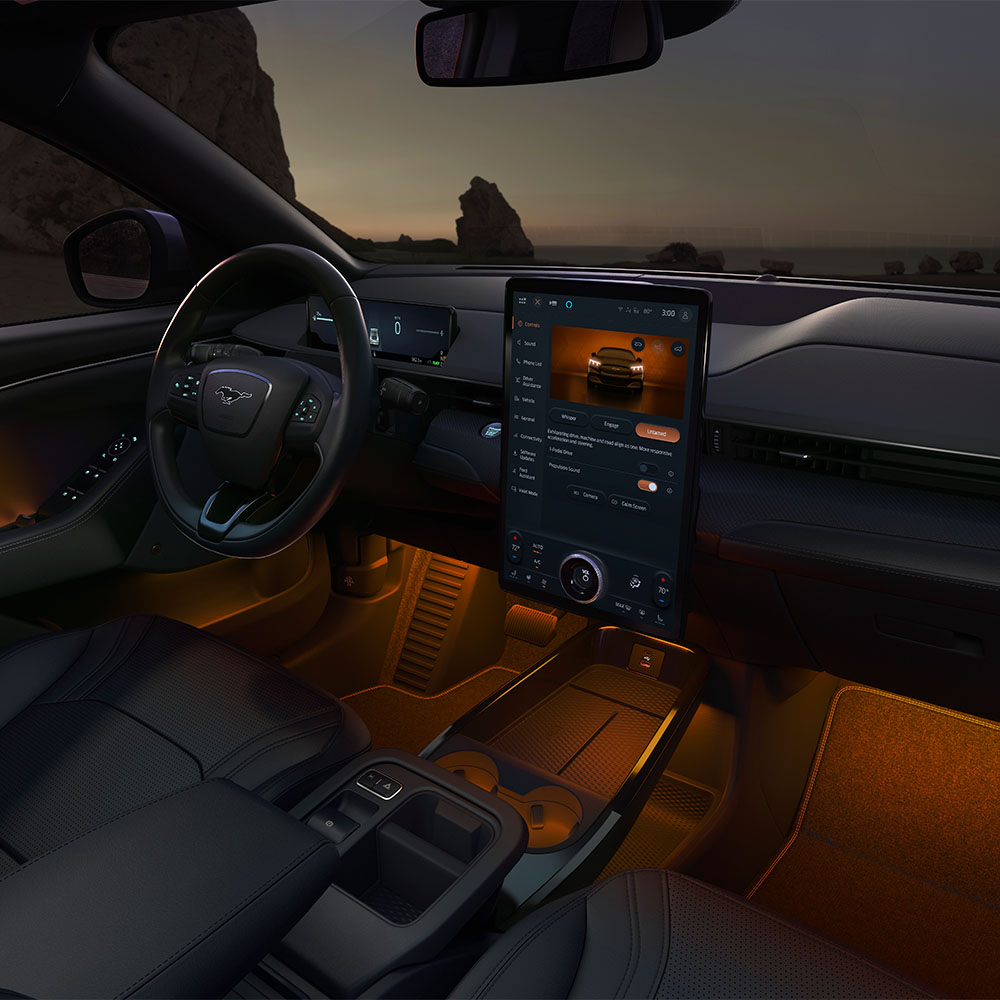 Interior do Ford Mustang Mach-E à noite, a mostrar o ecrã tátil SYNC 4 de 15,5" e a iluminação LED ambiente laranja