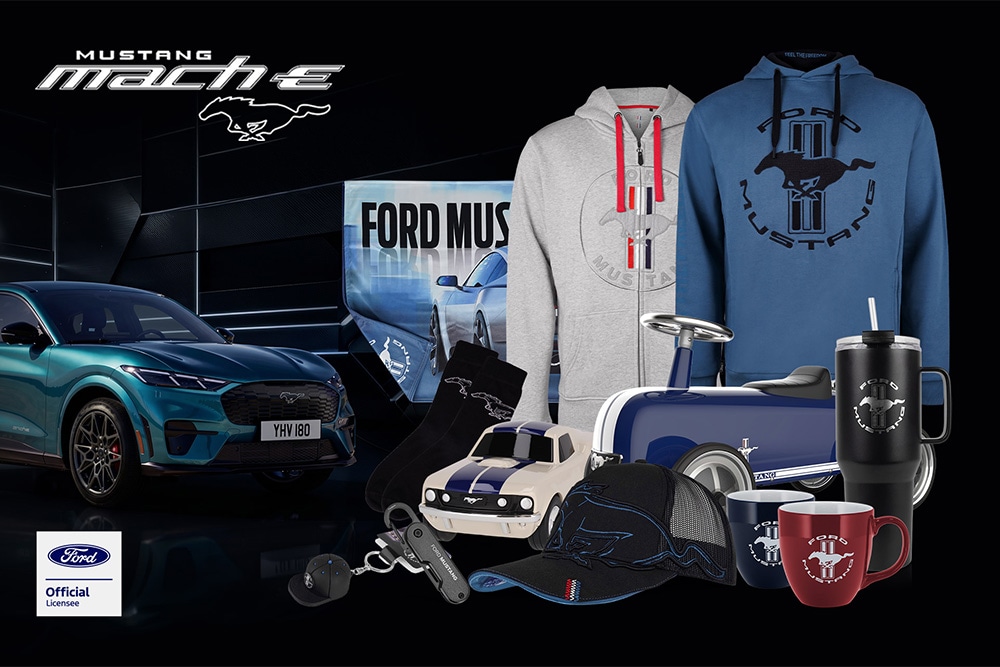 Ford merchandise collection featuring various Ford vehicles in the background with Ford branded umbrella, mugs, and clothing items.