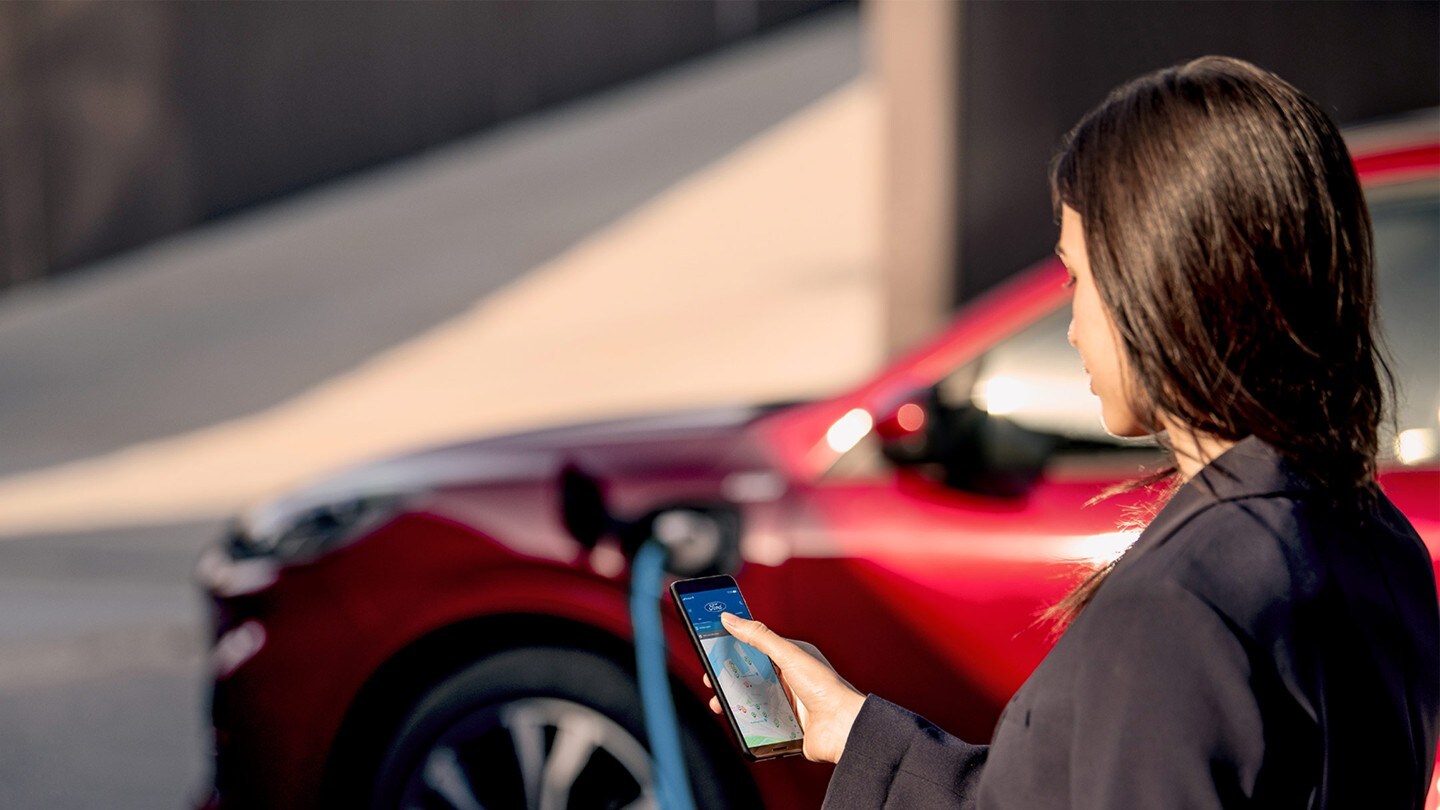 Mulher a ver o telemóvel enquanto carrega o Ford Kuga PHEV 