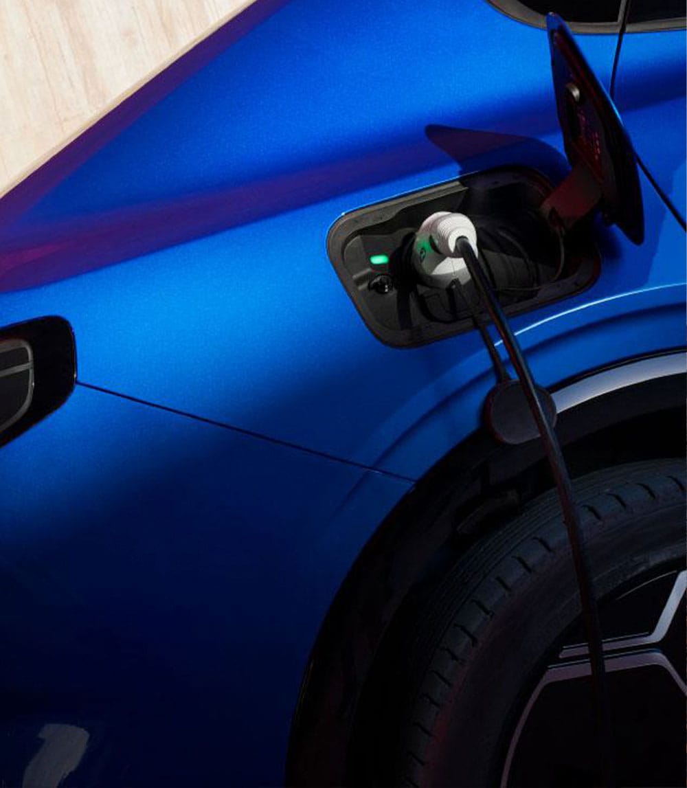 Grande plano da porta de carregamento de um veículo Ford azul com um cabo ligado.