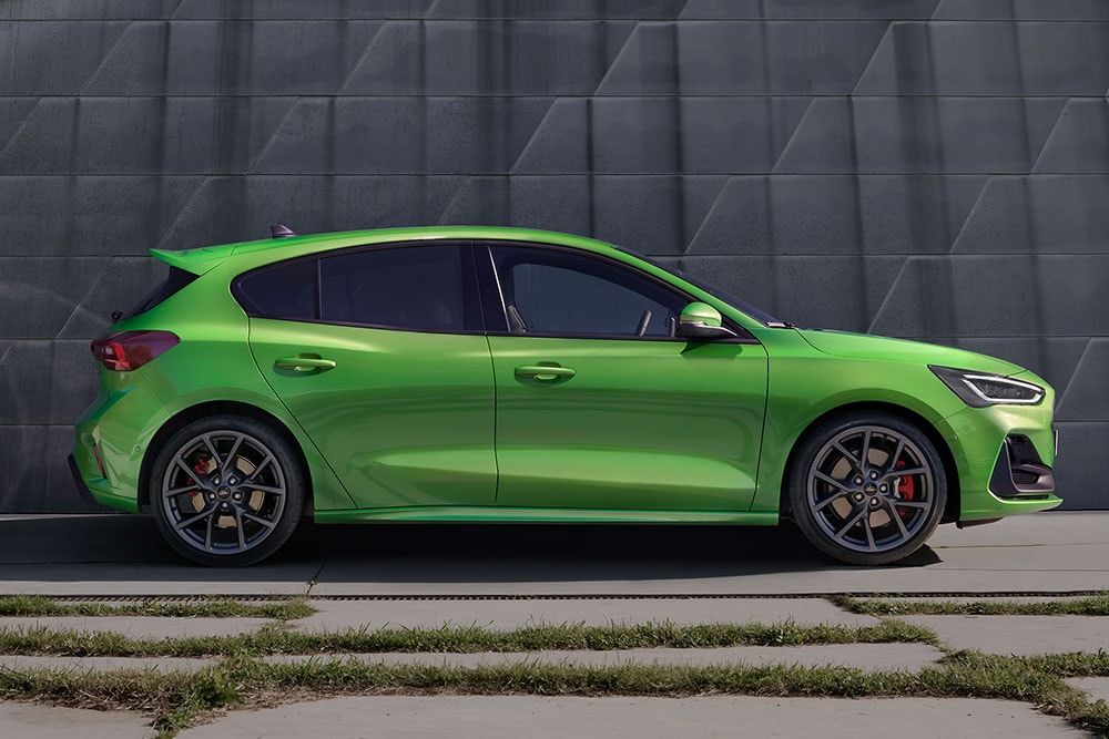 A lateral de um Ford Focus ST 5 portas verde médio estacionado fora de estrada.