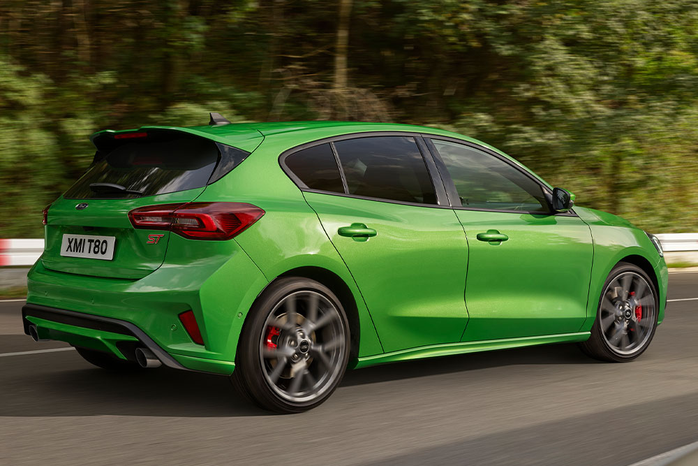 Vista traseira de um Ford Focus ST 5 portas verde médio dirigindo em uma pista de corrida.
