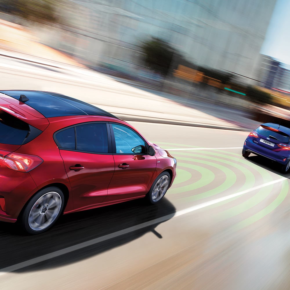 Um gráfico mostrando um Ford Focus vermelho usando sensores, indicados por linhas azuis, para detetar o carro da frente como parte do sistema de frenagem de emergência.