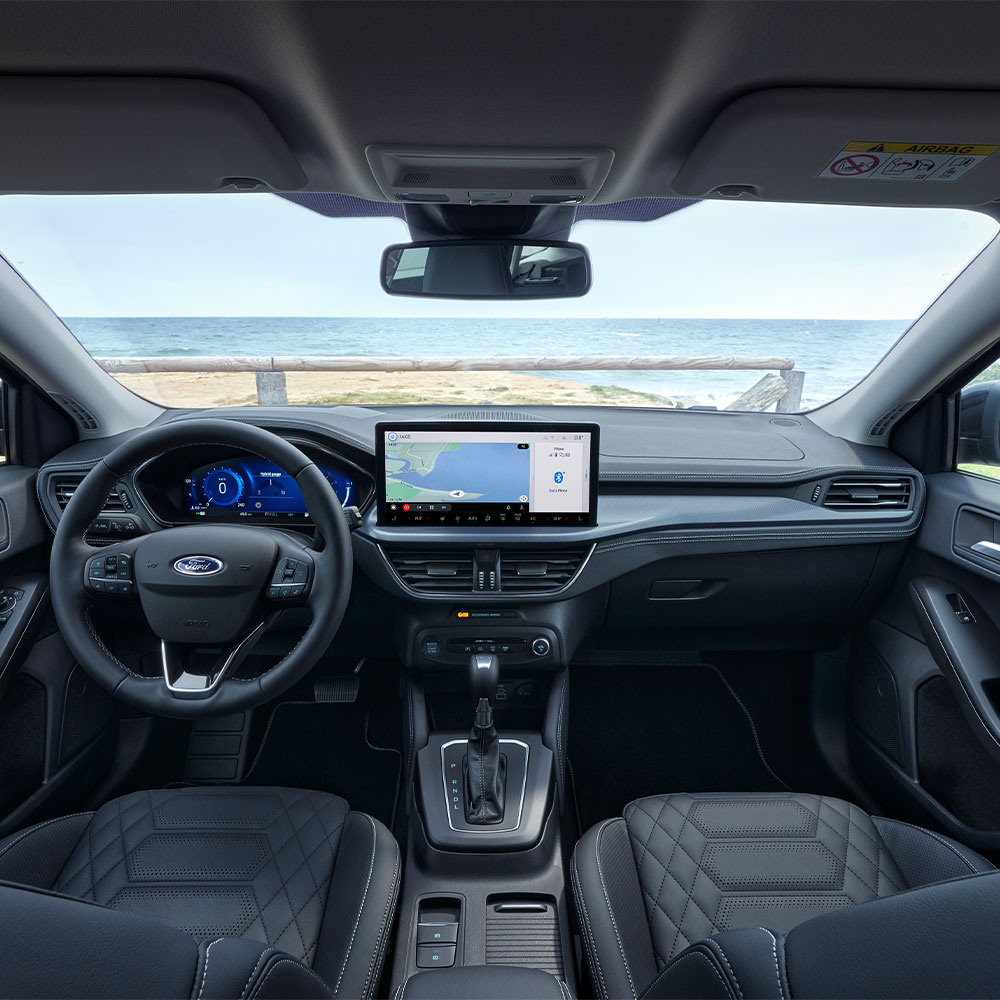 Vista interior do Ford Focus, mostrando o painel de instrumentos, volante e ecrã de infoentretenimento.