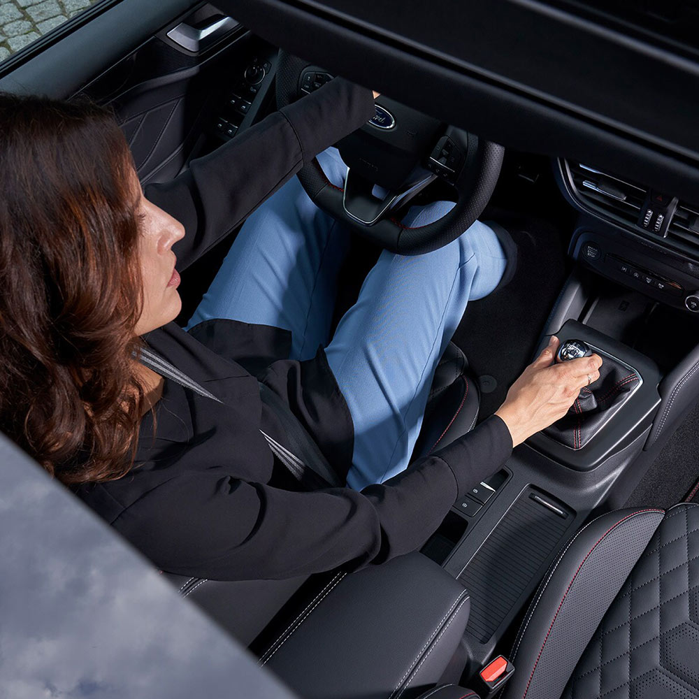 Uma visão aérea do motorista sentado no Ford Focus, tirada através do teto panorâmico de vidro.