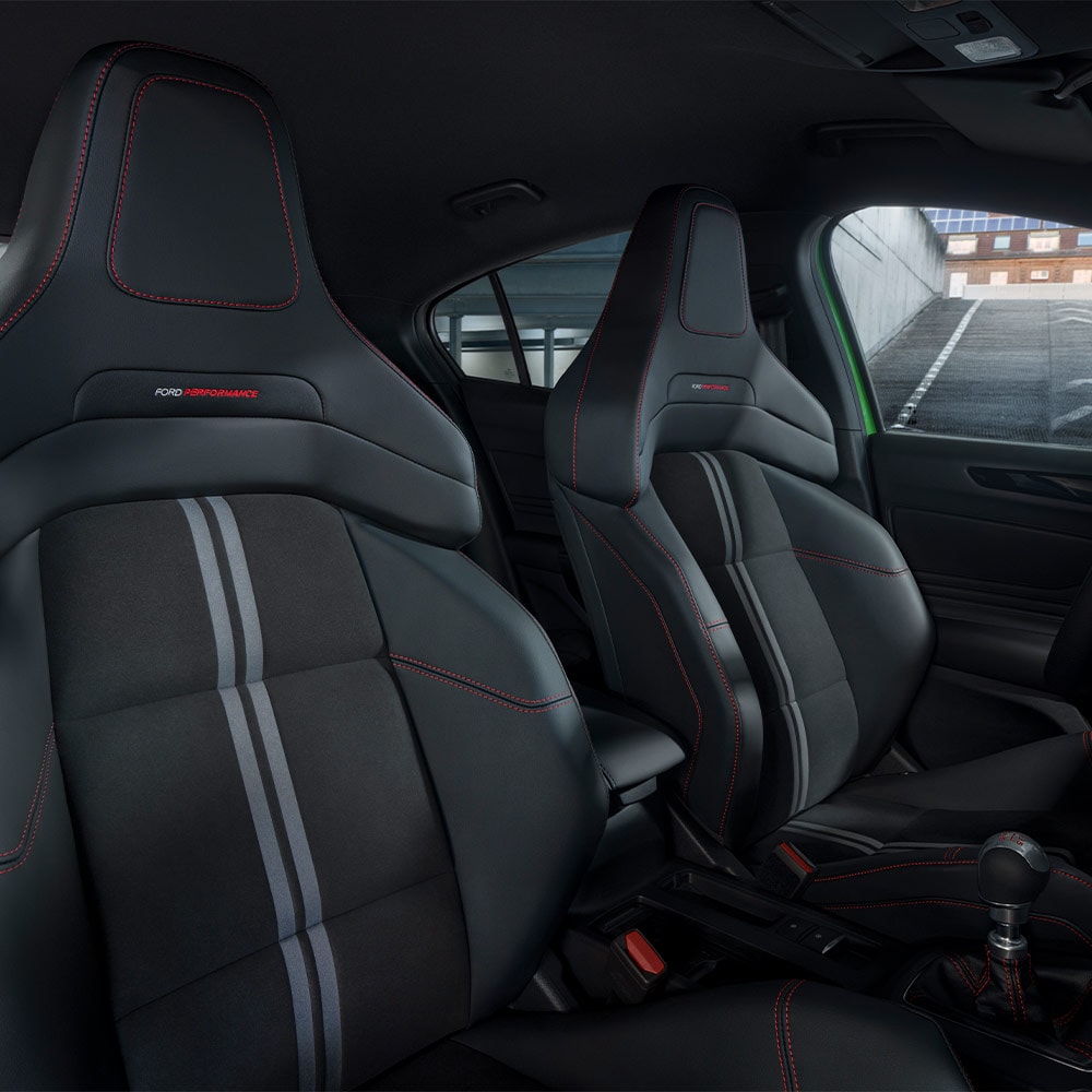 Um close acima dos bancos desportivos Ford Focus ST, com estofos escuros com costuras contrastantes vermelhas.