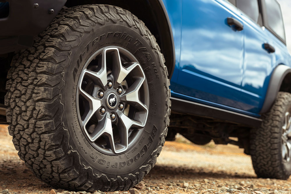 Grande plano dos pneus todo-o-terreno de um Ford Bronco azul.