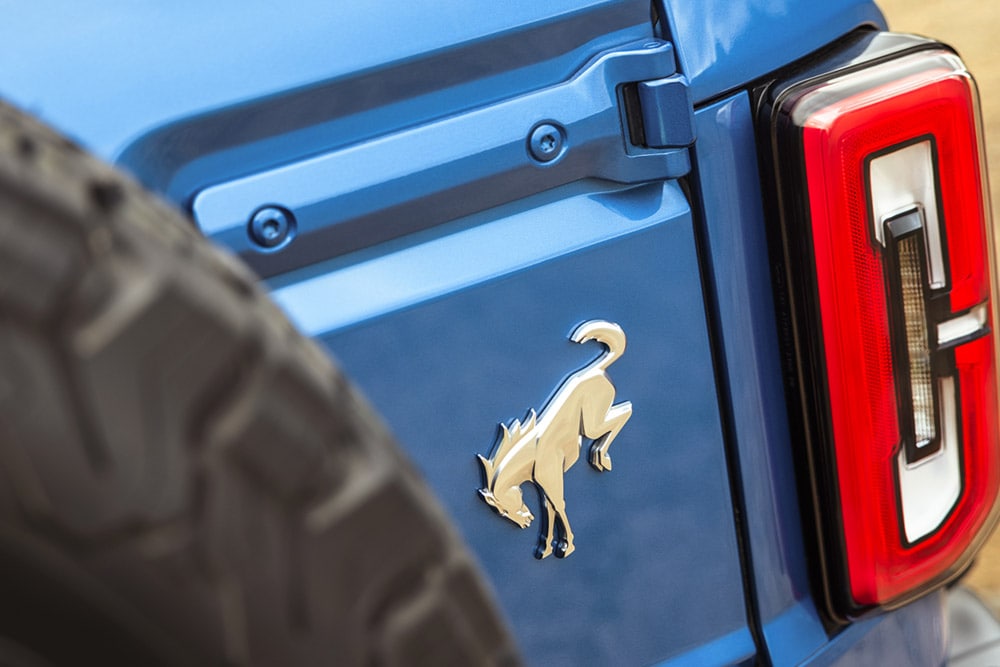 Grande plano dos detalhes com o símbolo da marca na parte traseira de um Ford Bronco azul.