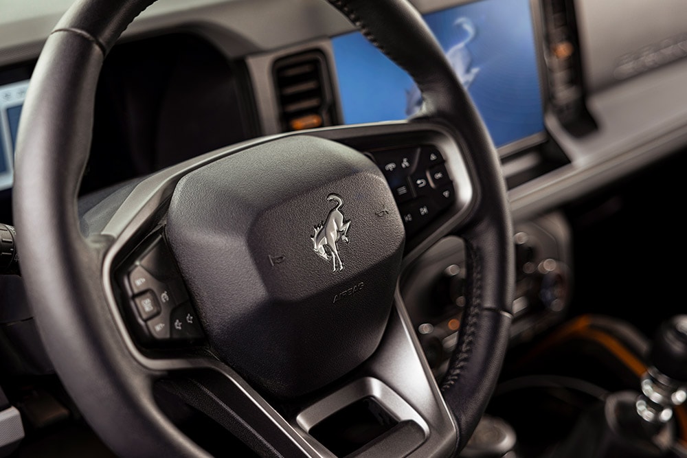 Grande plano do volante em pele com o símbolo da marca do Ford Bronco.
