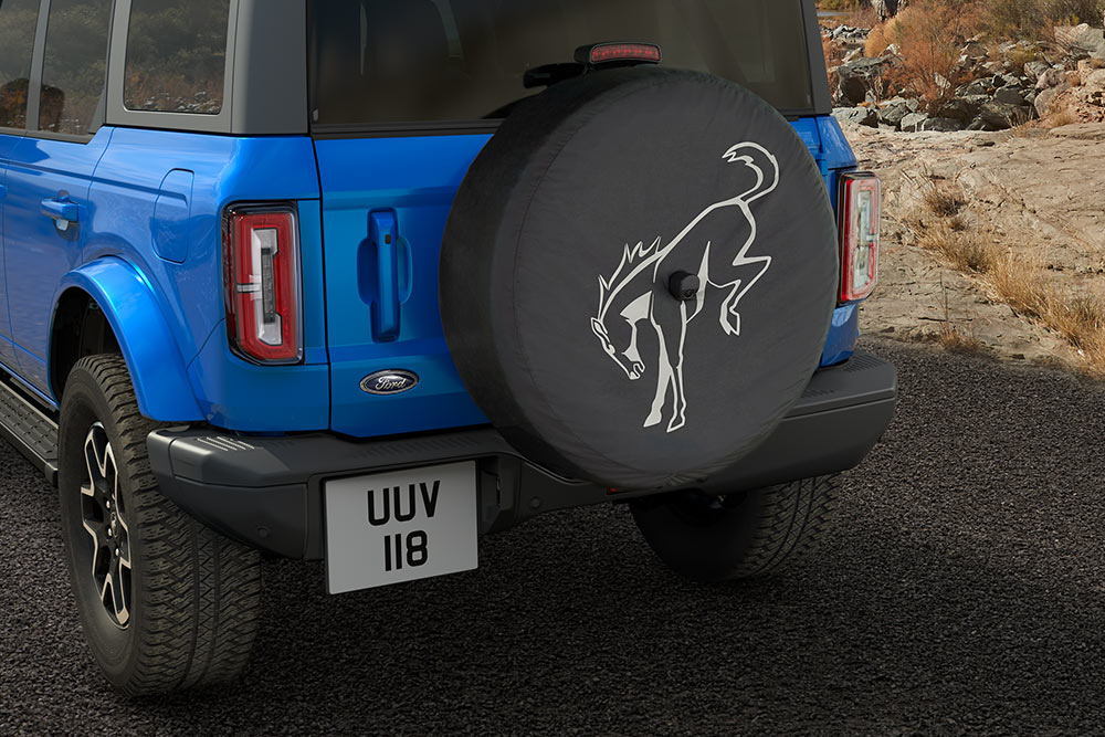 Vista da parte traseira de um Ford Bronco azul com um pneu sobressalente montado na parte traseira.