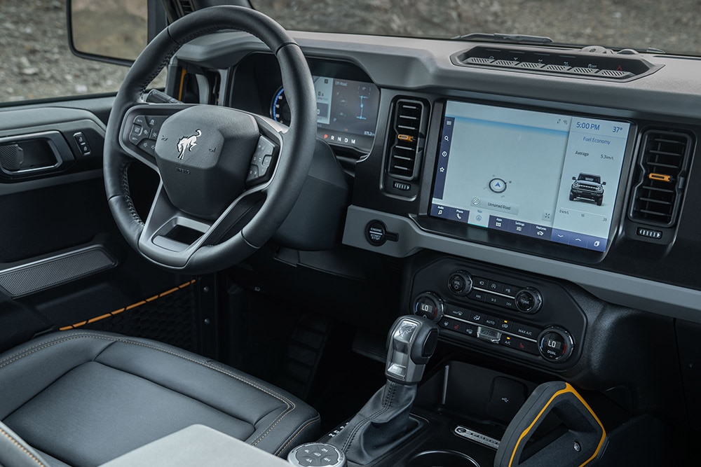 Vista do  interior do Ford Bronco, incluindo o volante em pele e o touchpad conectado.