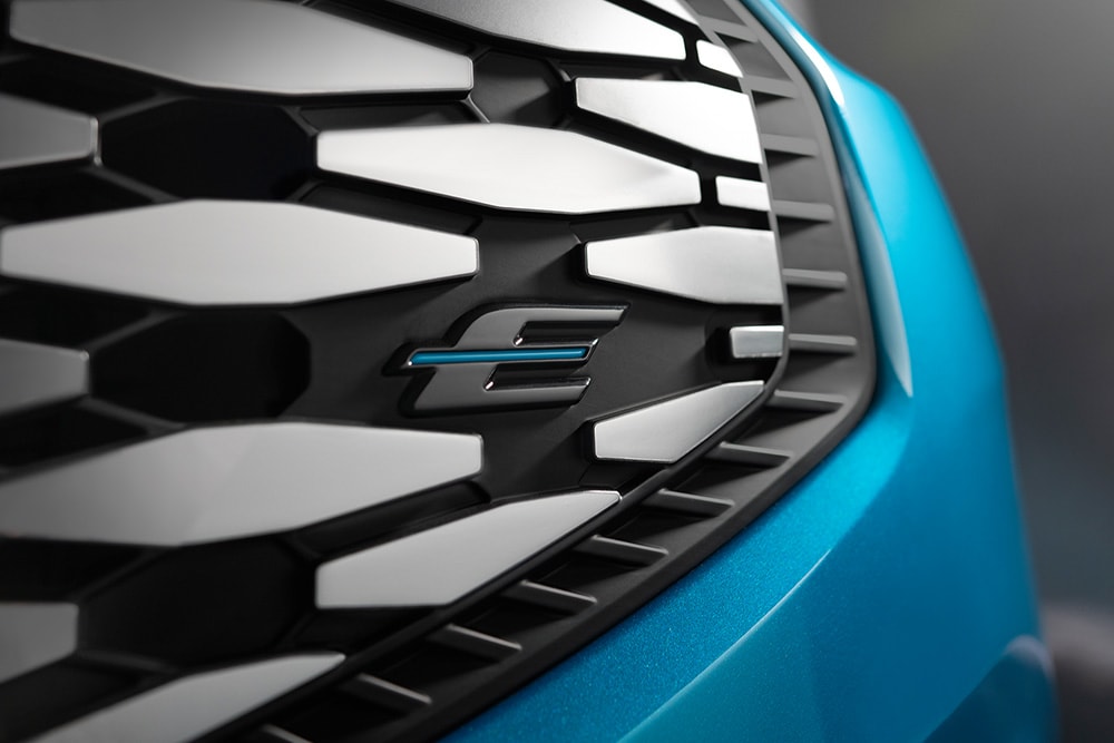 Grande plano da grelha do Ford E-Tourneo Custom, com o logótipo "E" azul exclusivo para veículos elétricos da Ford.