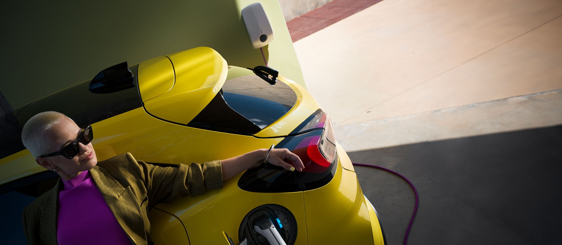 Grande plano da traseira de um Ford Puma Gen-E® elétrico amarelo, ligado a uma Wallbox doméstica.