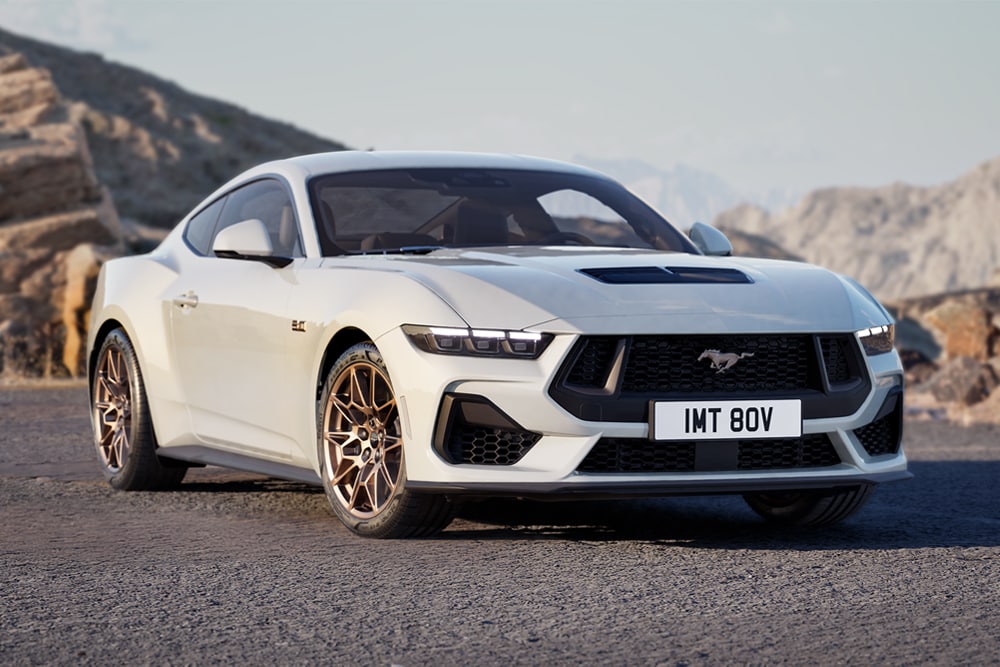 Um Ford Mustang GT Fastback com Bronze Pack em pintura Oxford White estacionado numa estrada de montanha.