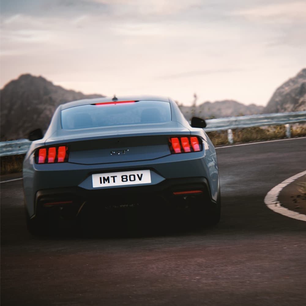 A traseira de um Ford Mustang GT Fastback com pintura Vapor Blue, a circular numa curva.