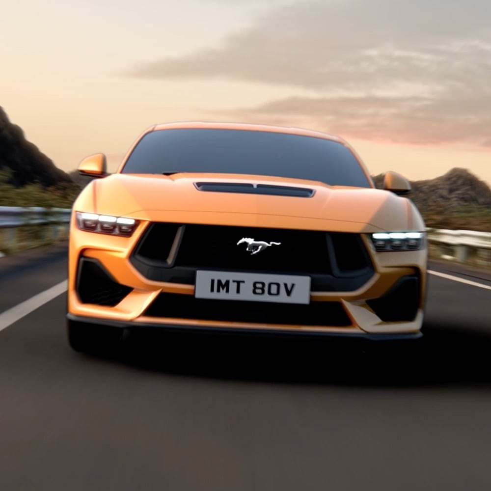 Vista frontal de um Ford Mustang laranja com close-up dos faróis, grelha e emblema Mustang