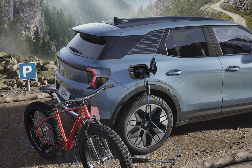 Uma bicicleta elétrica a carregar a partir de uma Ford Explorer®, paisagem montanhosa ao fundo.