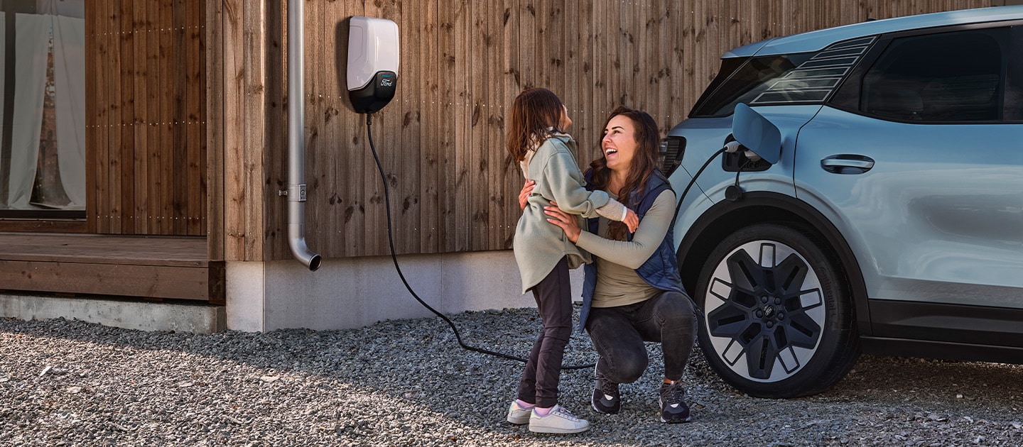 Mãe e filha junto ao Ford Explorer a carregar em casa