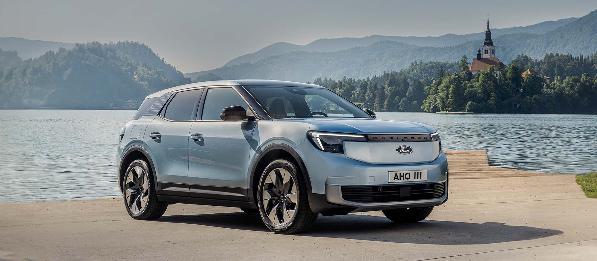 O novo Ford Explorer® 100% elétrico em Arctic Blue, estacionado junto a um lago.