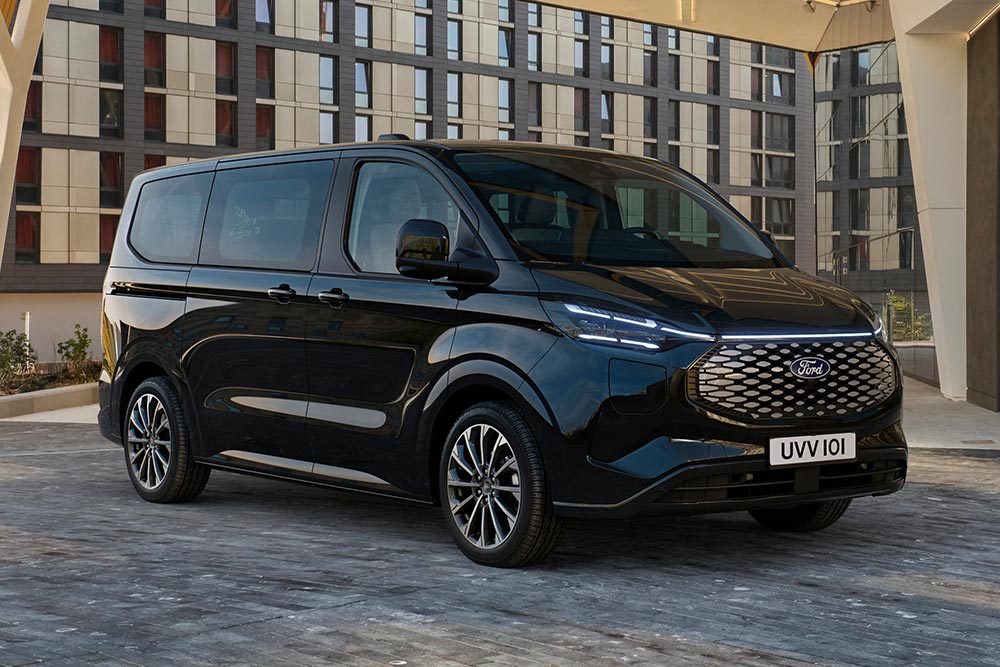 Ford E-Tourneo Custom preto estacionado em frente a um edifício moderno.