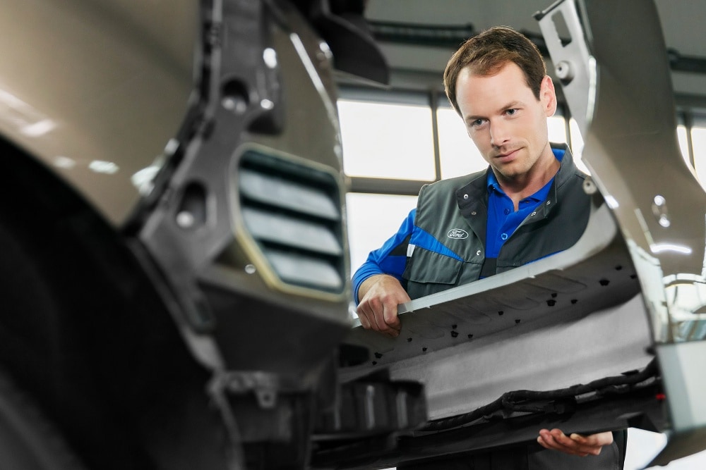 Um técnico da Ford Service substitui o para-choques dianteiro de um carro.