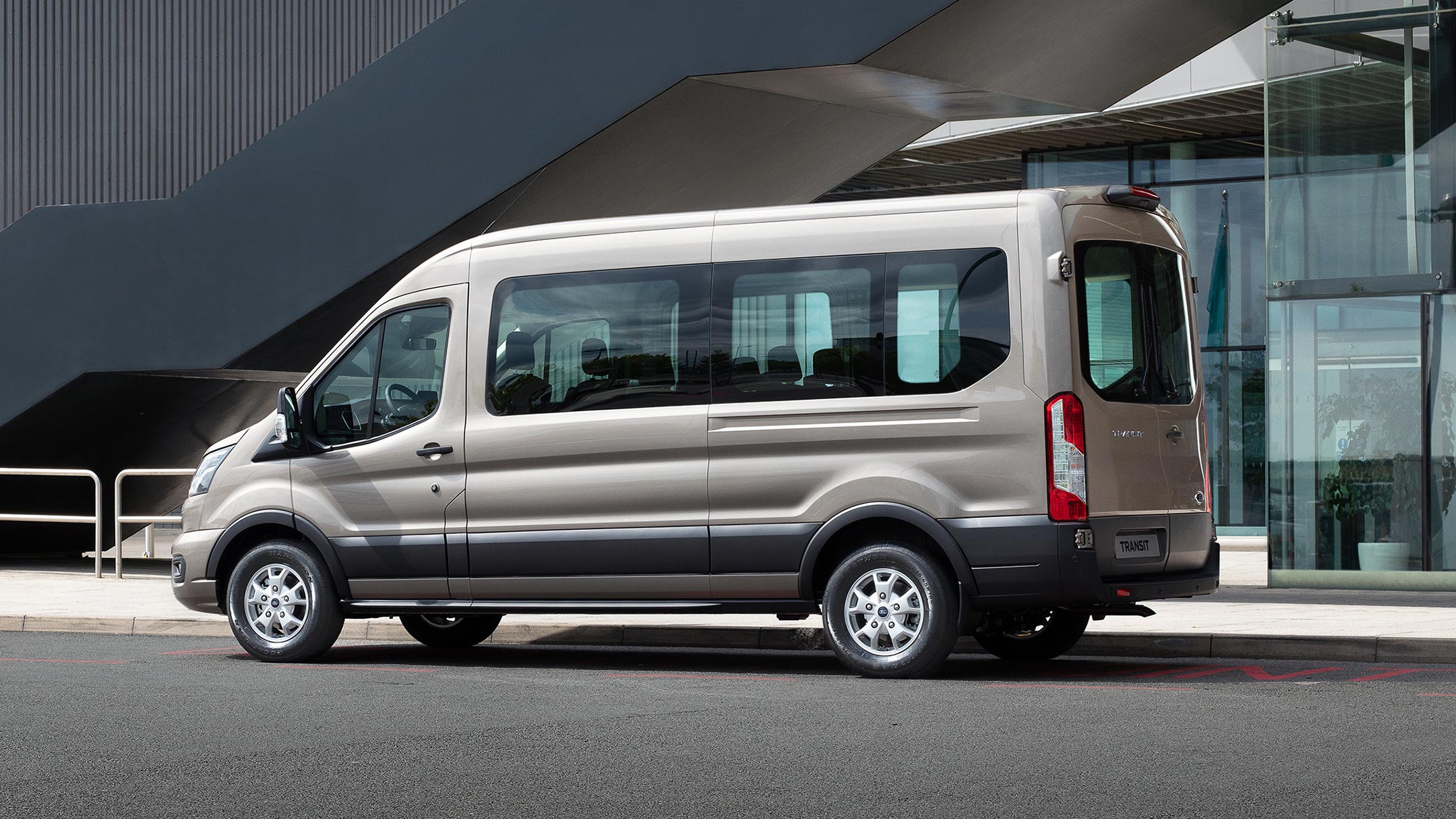 Vista lateral da Ford Transit Kombi estacionada ao lado de um edifício moderno.