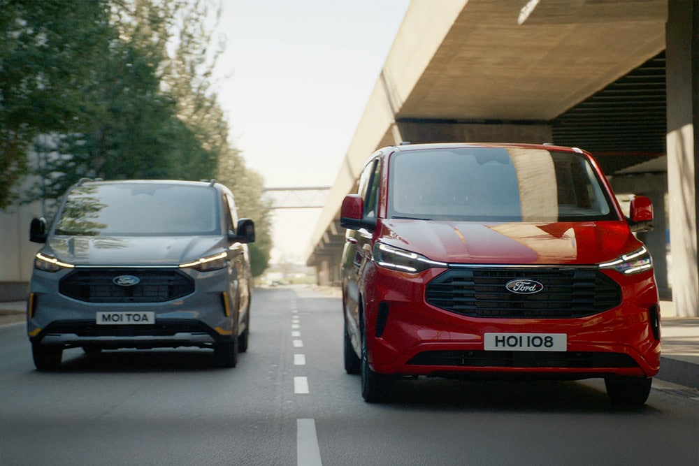 Ford Transit Custom cinzenta e vermelha a circular numa autoestrada.