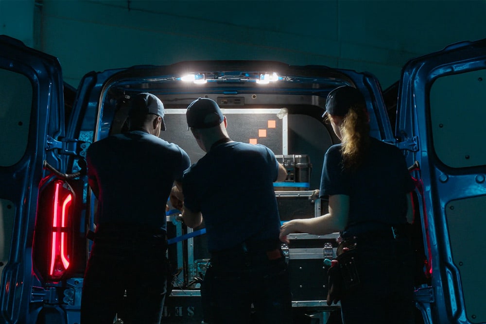 Três pessoas a trabalharem na traseira de uma Ford E-Transit Custom.