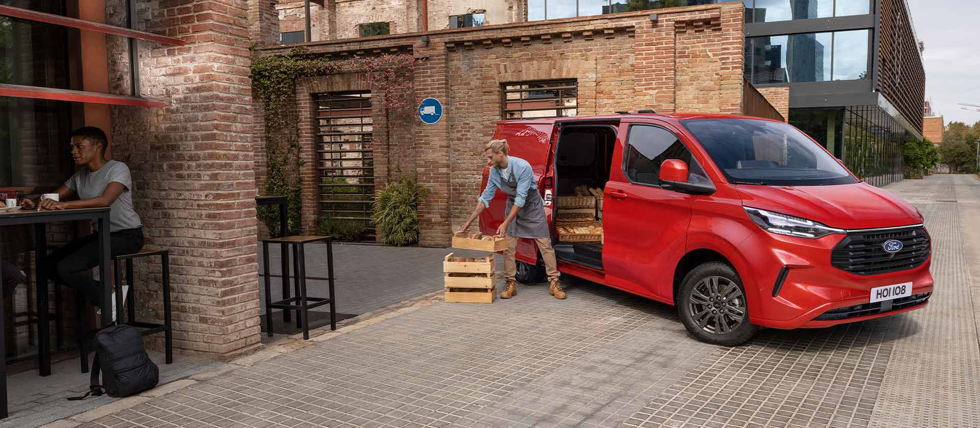 Ford Transit Custom vermelha estacionada à porta de um café.