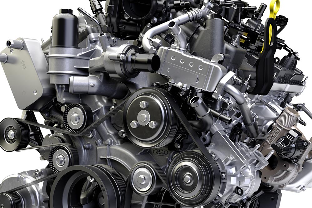 Grande plano do motor de um veículo, mostrando várias correias, polias e componentes mecânicos.