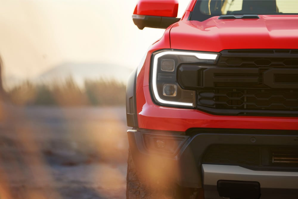 Grande plano da grelha frontal de um Ford Ranger Raptor vermelho.