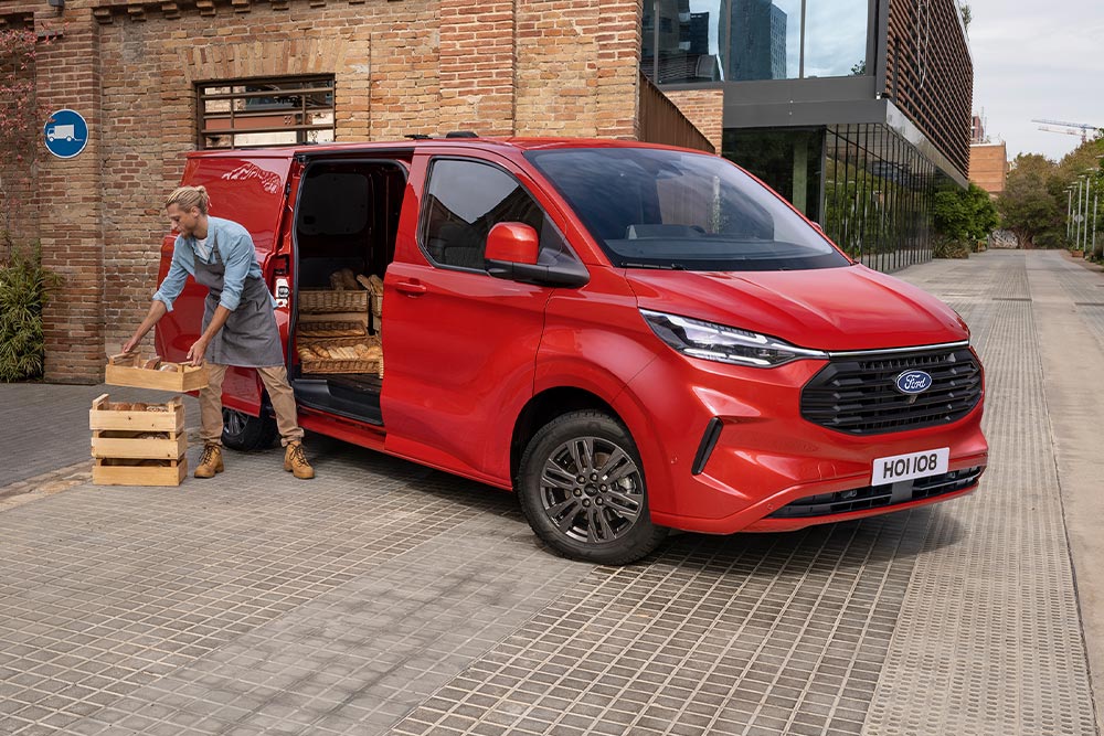 Estafeta a carregar encomendas para um Ford Transit Custom vermelho.